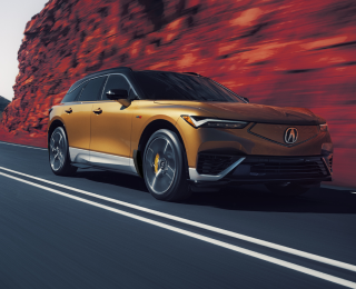 Plan de trois quarts avant en plongée d’un ZDX or roulant sur une autoroute de montagne. Une partie de l’image est saturée de couleur, de sorte que la poussière sur les côtés de l’autoroute est rouge.