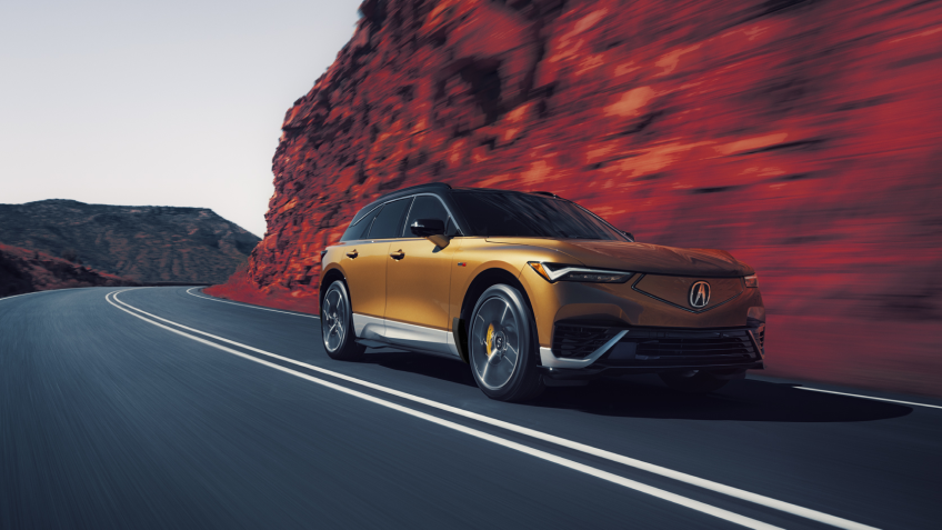 Plan de trois quarts avant en plongée d’un ZDX or roulant sur une autoroute de montagne. Une partie de l’image est saturée de couleur, de sorte que la poussière sur les côtés de l’autoroute est rouge.