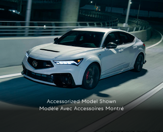 Plan de trois quarts latéral d’une Integra Type S blanche effectuant un virage sur une bretelle d’autoroute la nuit.