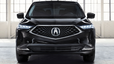 Front-facing shot of a black Acura MDX parked in a large, empty white garage space featuring loft-style windows and white brick walls.	Vue avant d’un Acura MDX noir stationné dans un grand garage blanc vide muni de fenêtres de style loft et de murs de briques blanches.